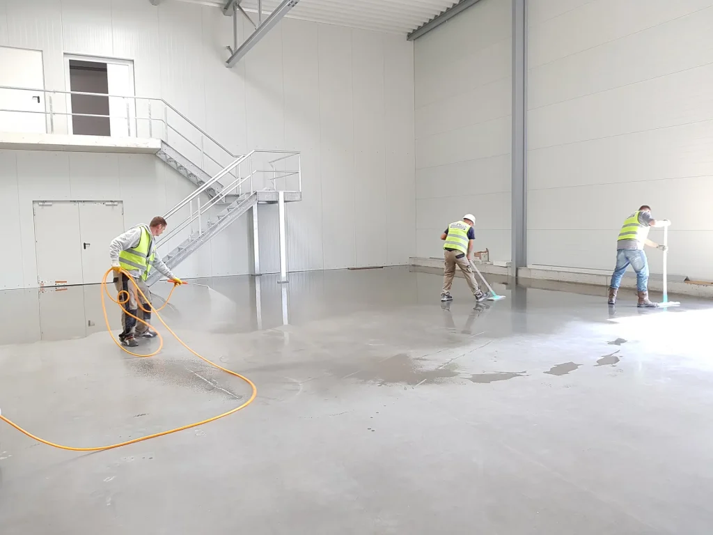 Arbeiter in Warnwesten reinigen eine Halle